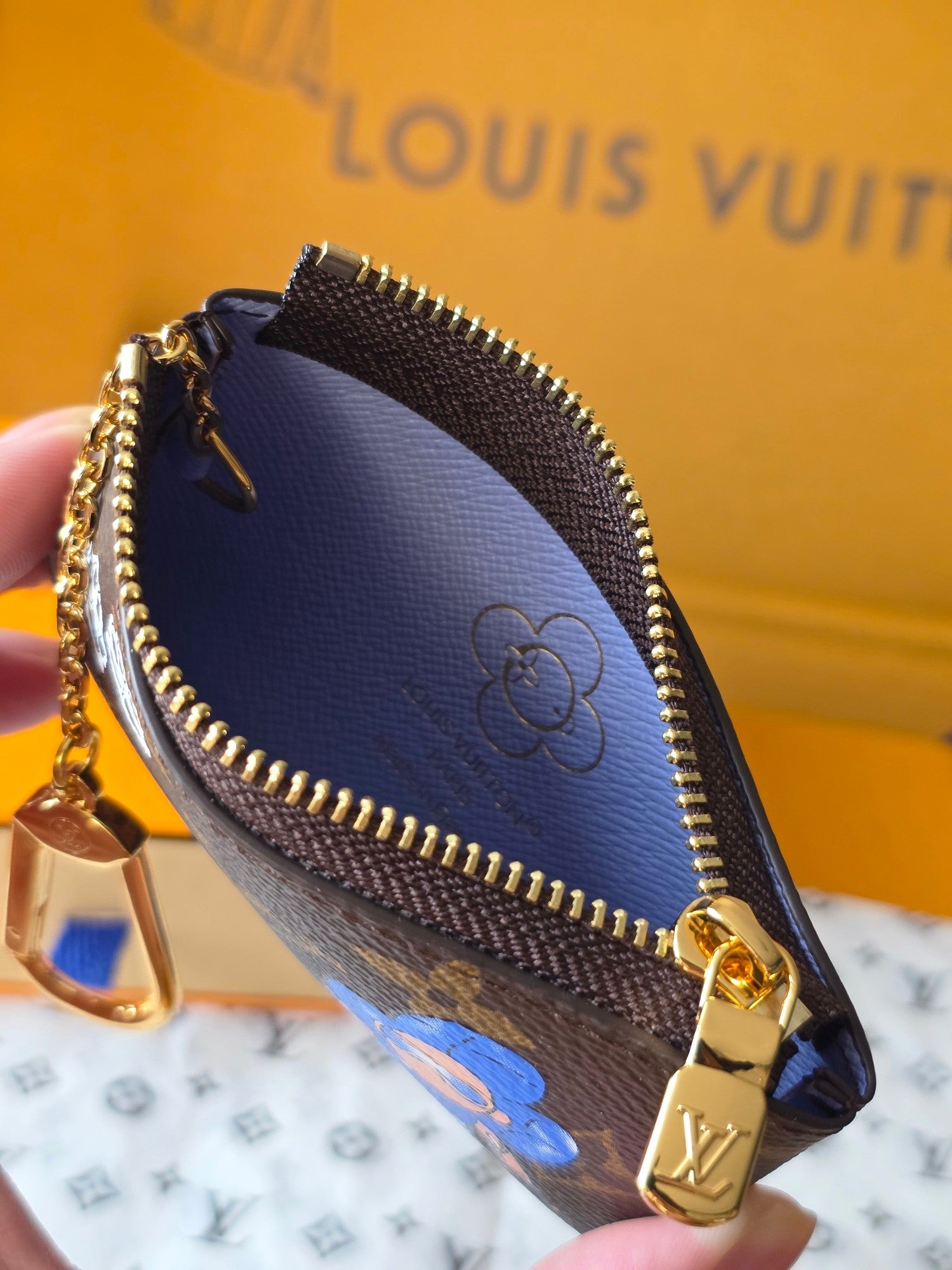 Louis Vuitton small bag close-up with gold clasp and blue inner lining detail.
