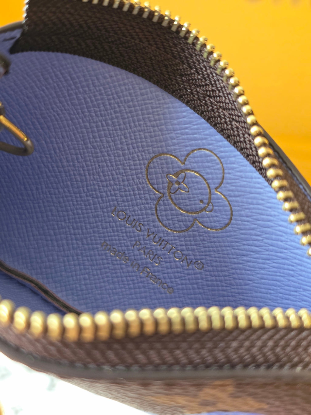 Louis Vuitton small bag close-up of embossed clover logo on blue leather lining.