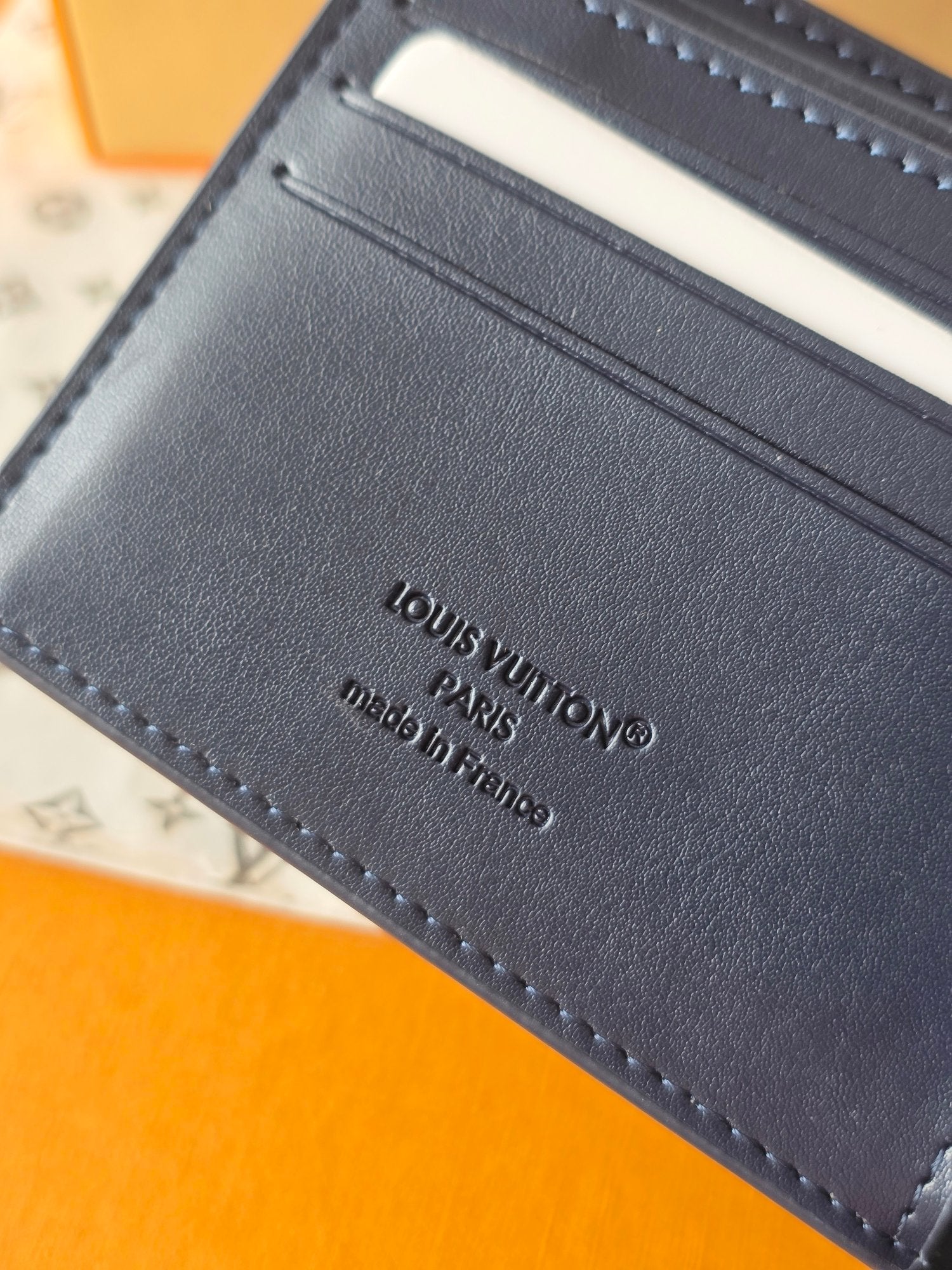 Small bag: Louis Vuitton blue leather card wallet close-up of stamped brand text