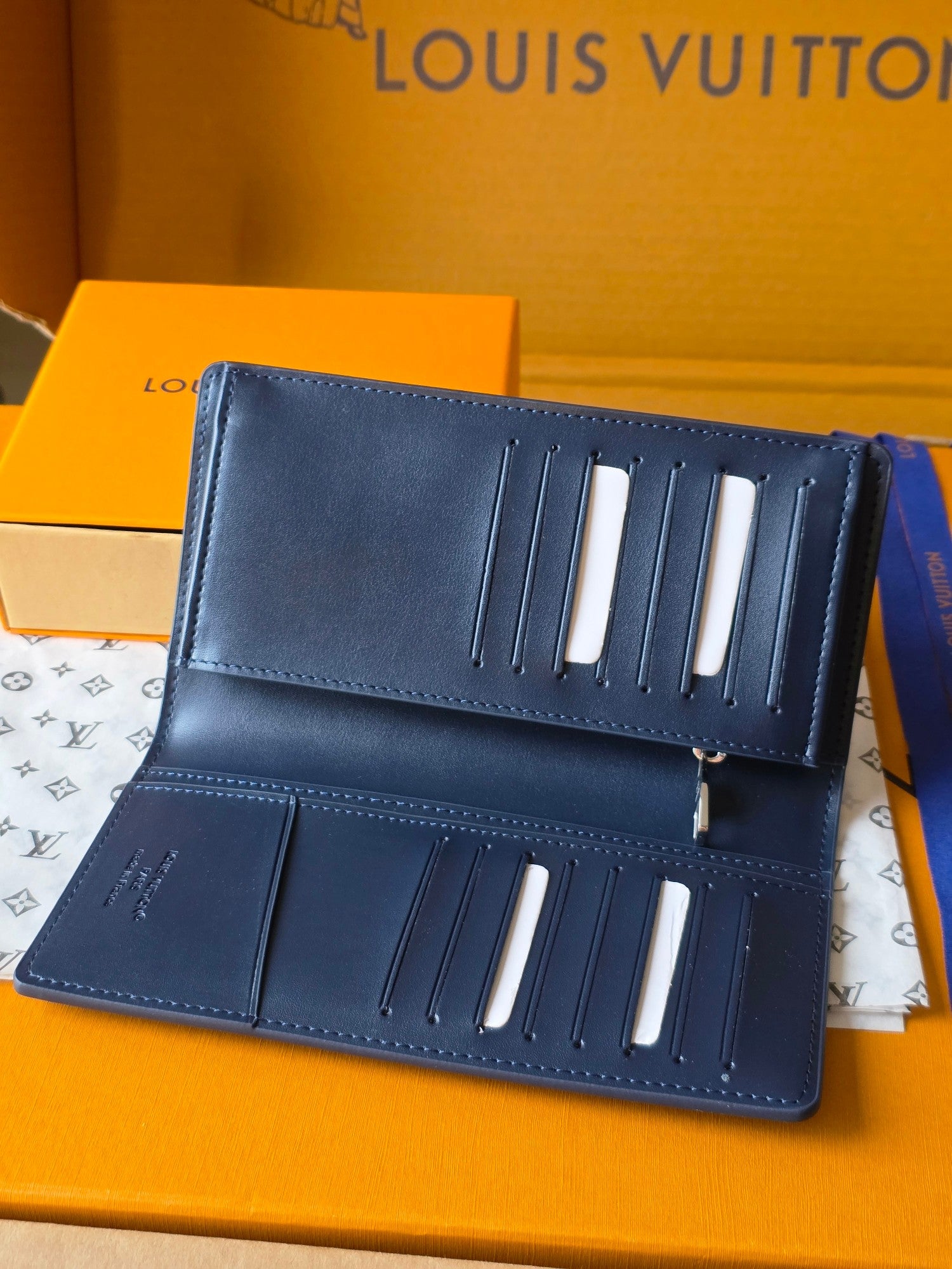 Small leather wallet open, showing card slots and patterned interior lining