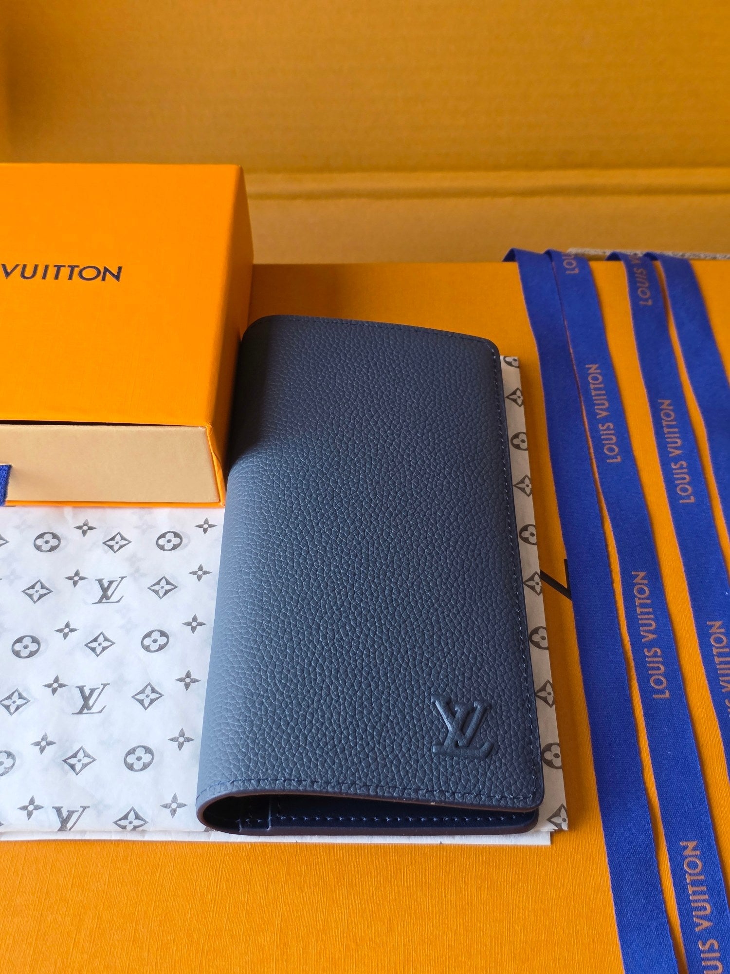 Small leather wallet with dark blue pebbled finish and open interior pocket