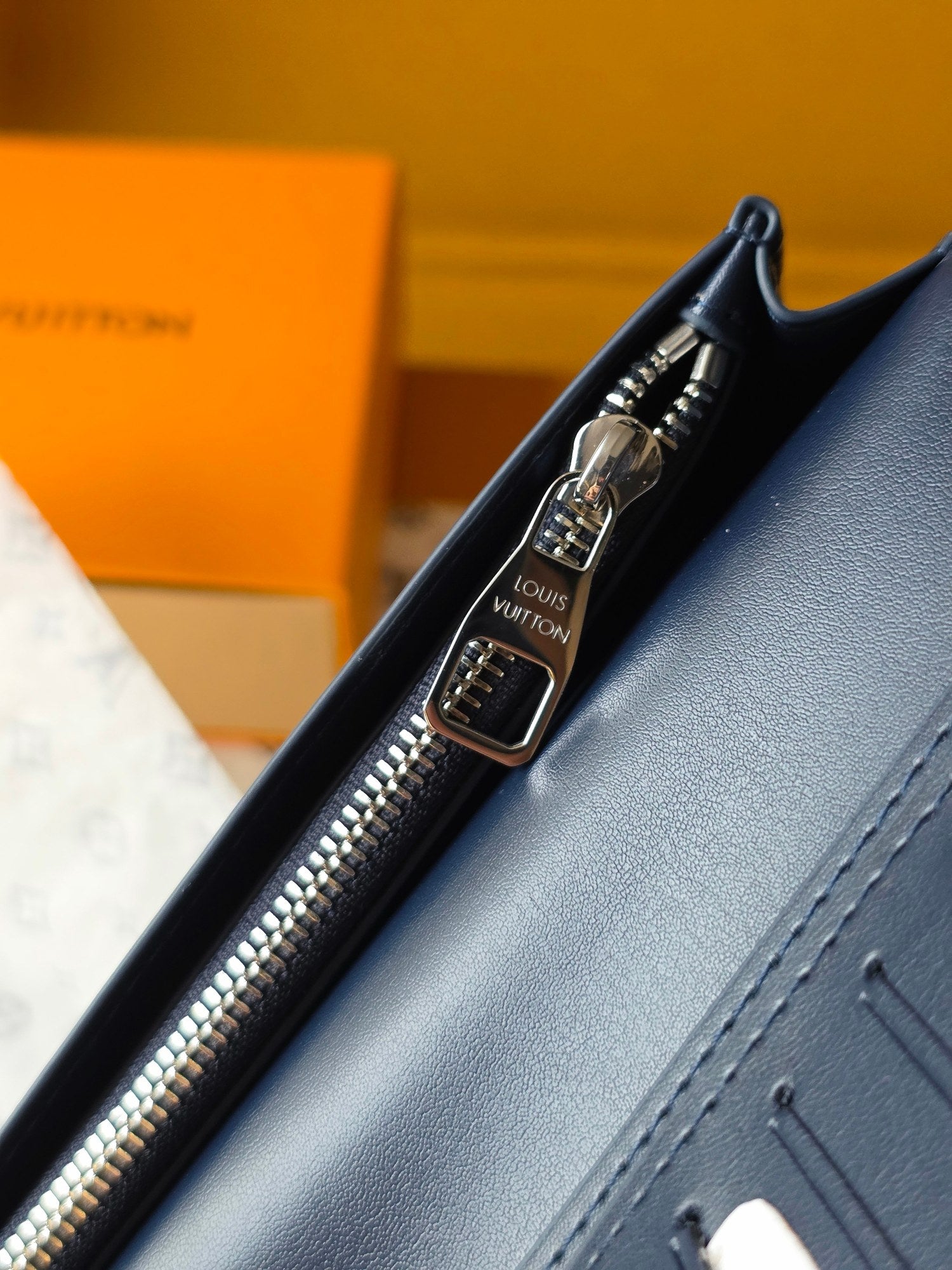 Small leather wallet close-up of zipper pull, metal rings, and stitched edge