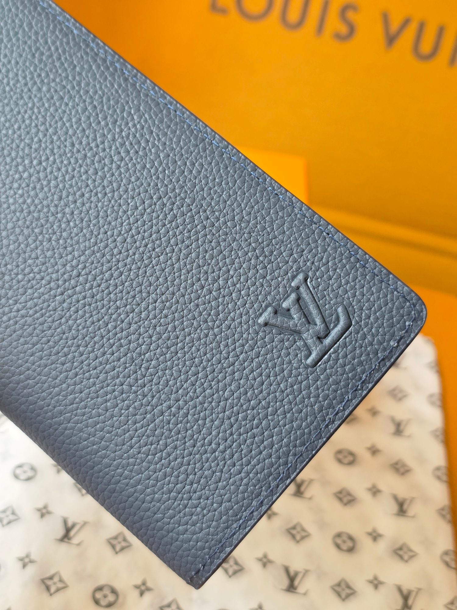 Small leather wallet corner detail with embossed LV logo and pebbled texture