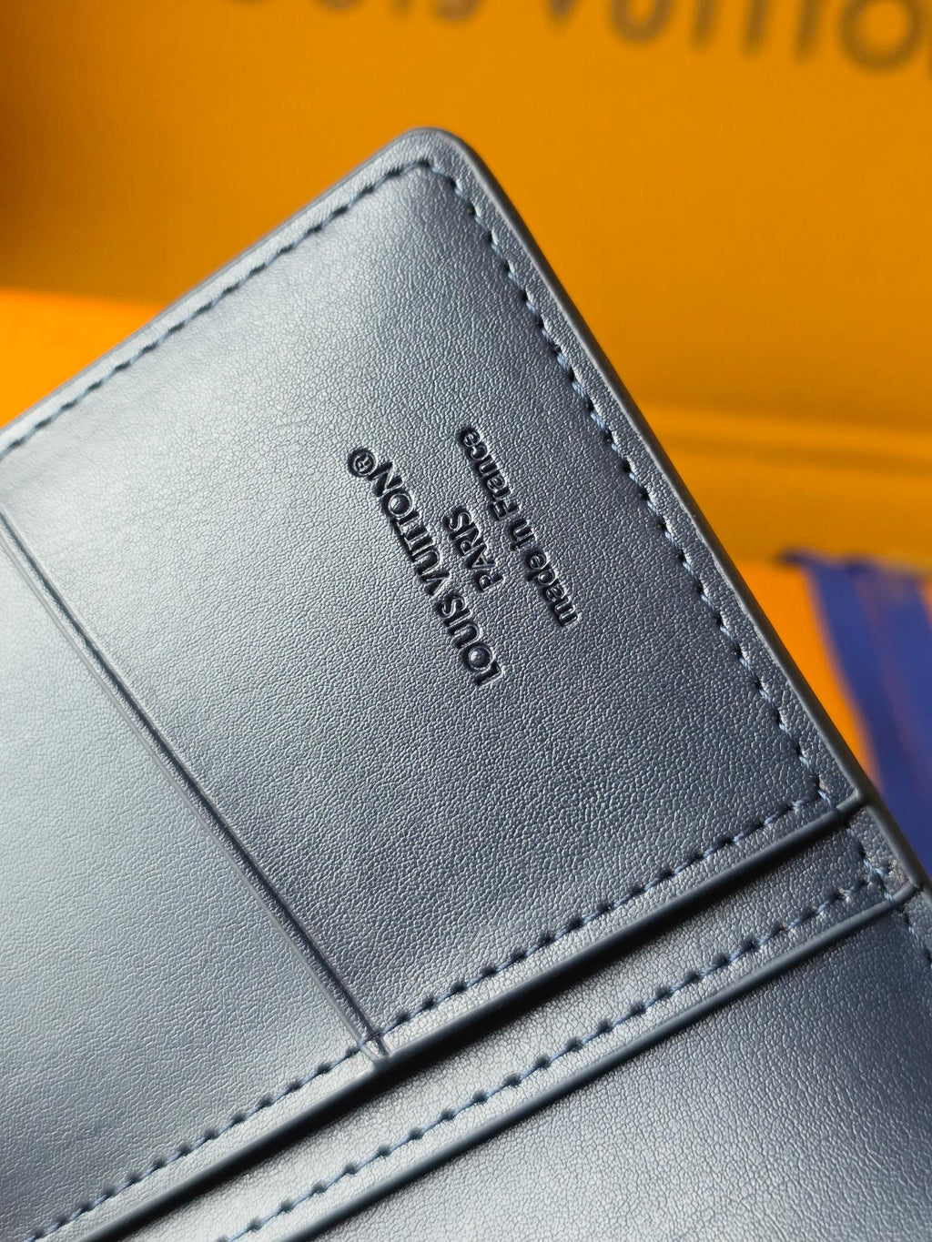Small leather wallet back close-up with embossed text and stitched border