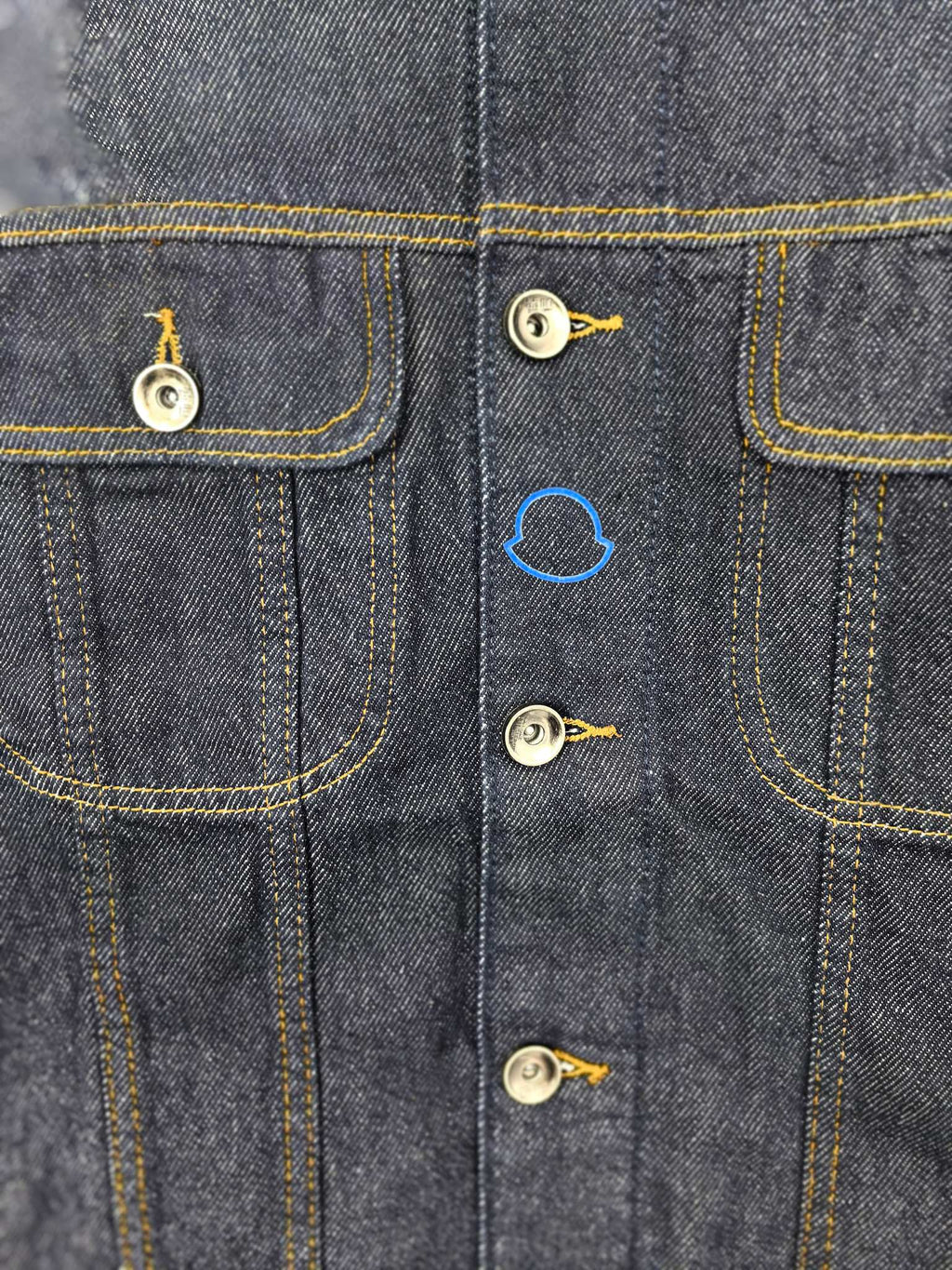 Moncler dark denim jacket front close-up with flap pockets and metal button details