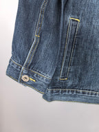 Blue denim jacket lower hem close-up with side pocket and strap detail