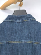 Blue denim jacket back yoke close-up with stitched collar seam