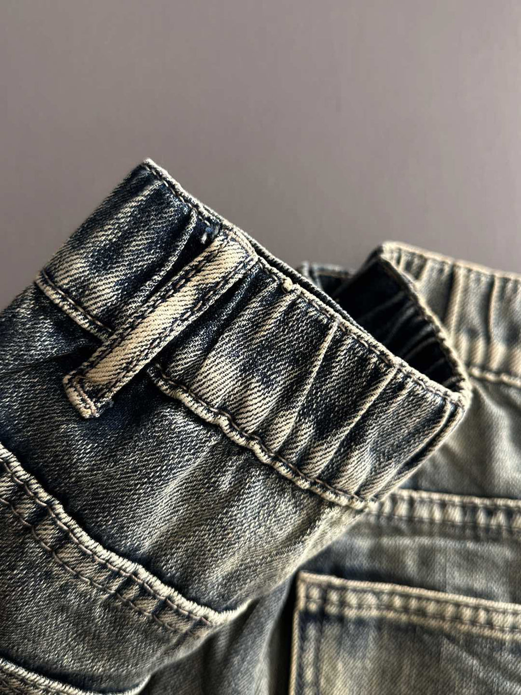 Denim pants pocket and waistband close-up with belt loops and button