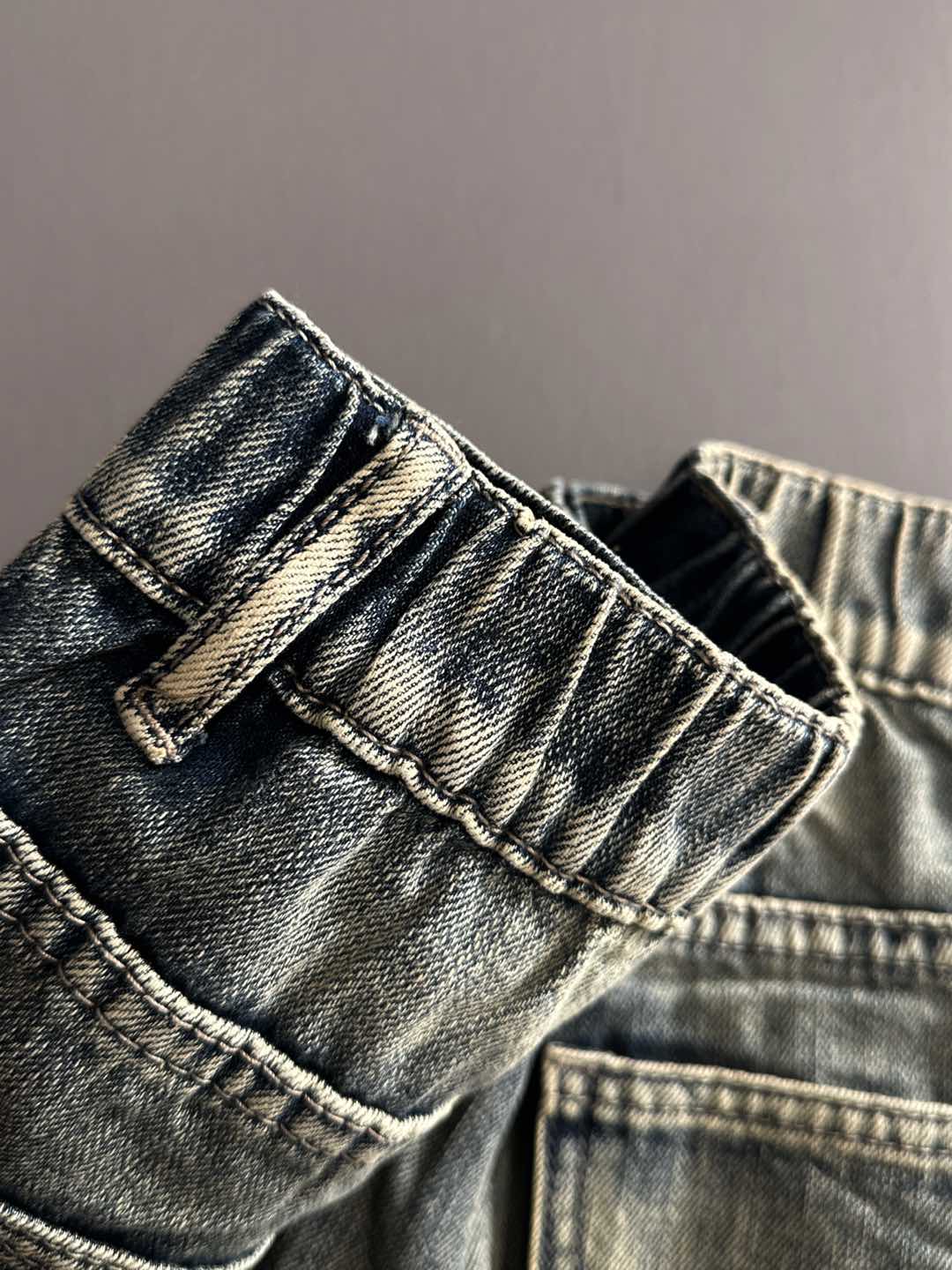 Denim pants pocket and waistband close-up with belt loops and button