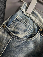 Front neckline close-up on light wash denim pants with button and belt loops