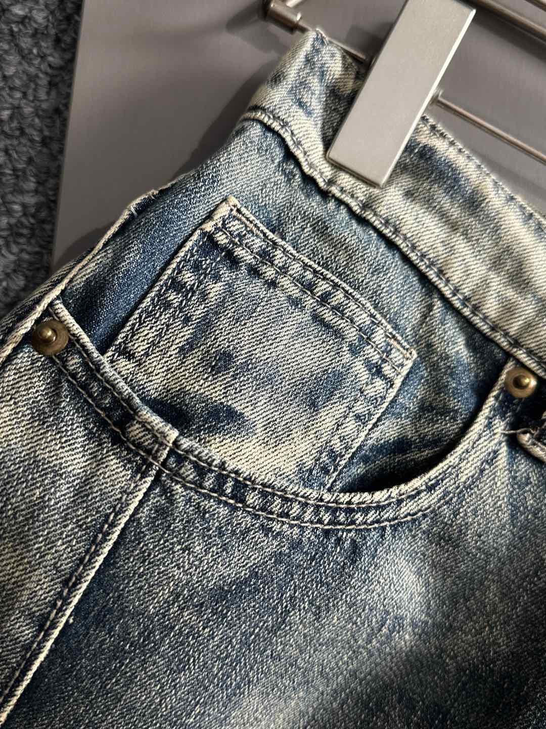 Front neckline close-up on light wash denim pants with button and belt loops