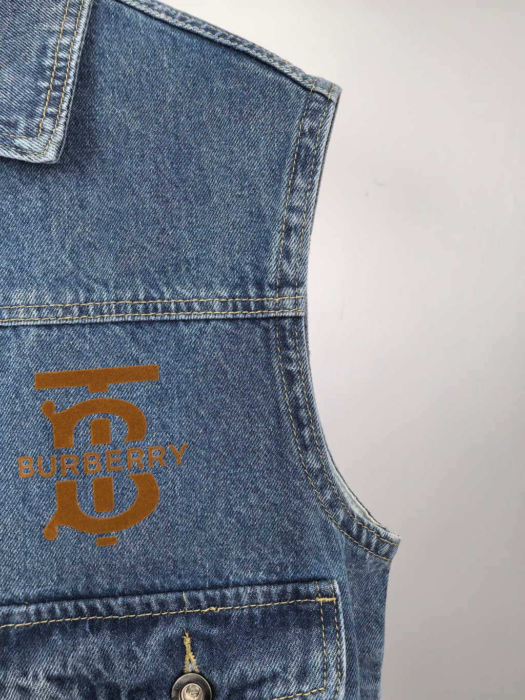 Burberry denim vest chest area with gold logo patch and stitched pocket