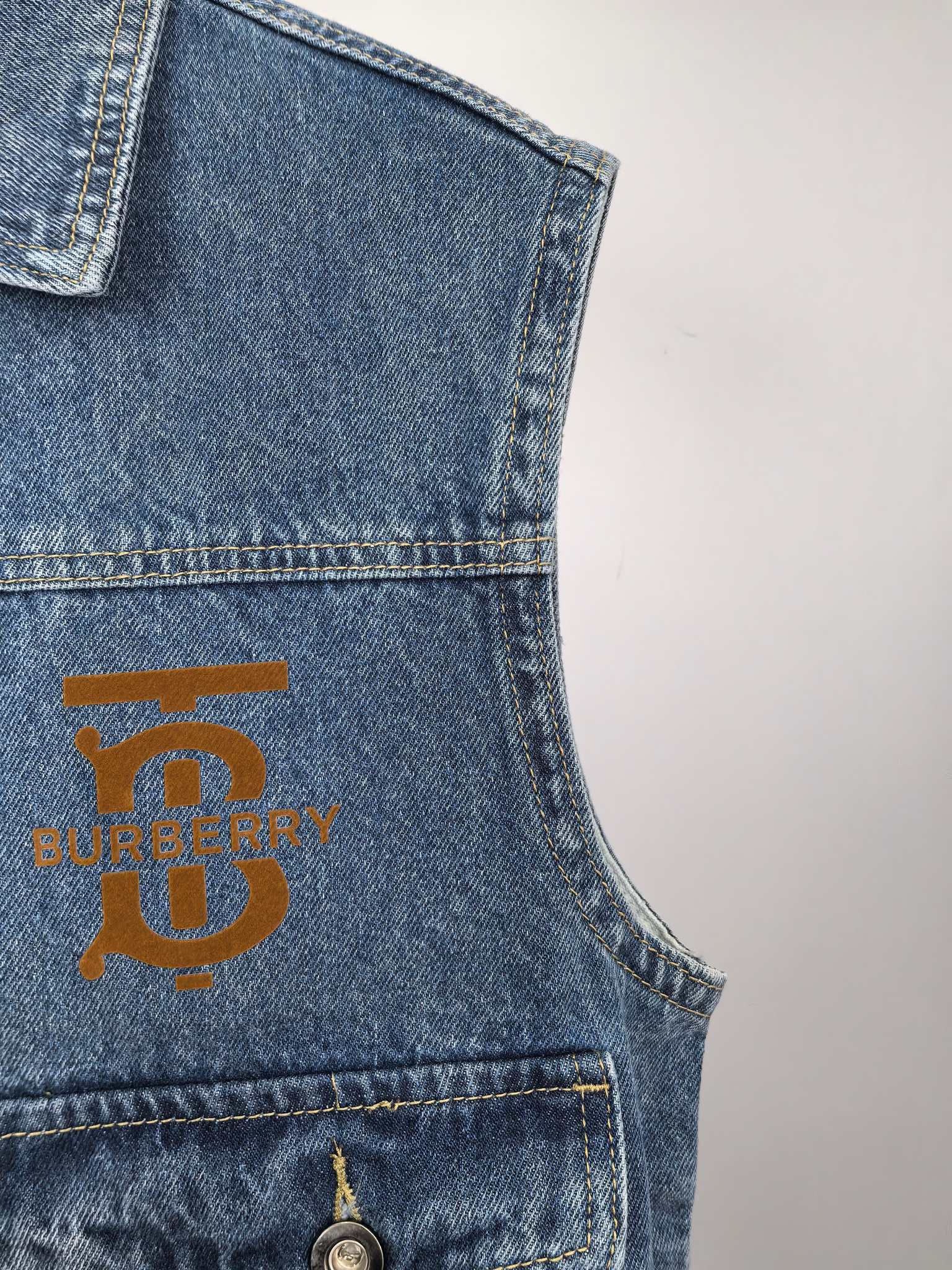 Burberry denim vest chest area with gold logo patch and stitched pocket