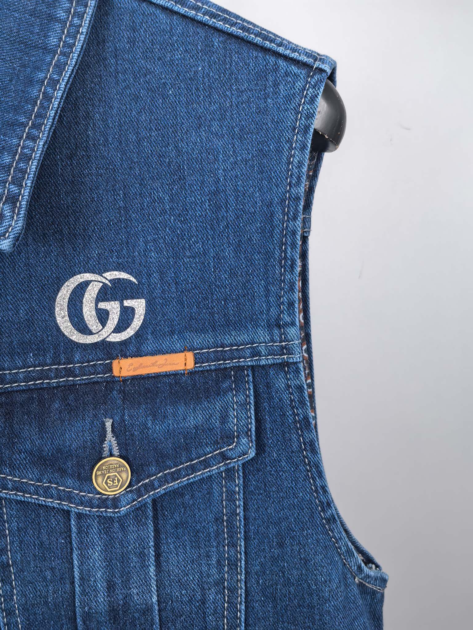 Gucci blue denim vest detail with GG logo patch, button closure, and chest pocket