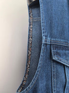 Gucci blue denim vest side seam close-up with buttoned pocket and curved stitching