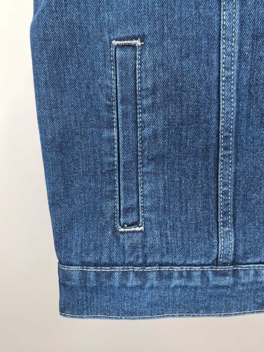 Gucci blue denim vest back lower section with vertical seam and pocket edge