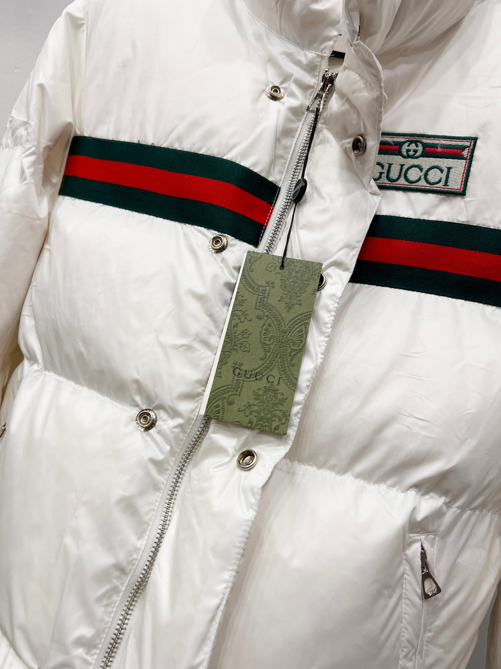 Gucci white puffer jacket close-up with front zipper and stripe trim