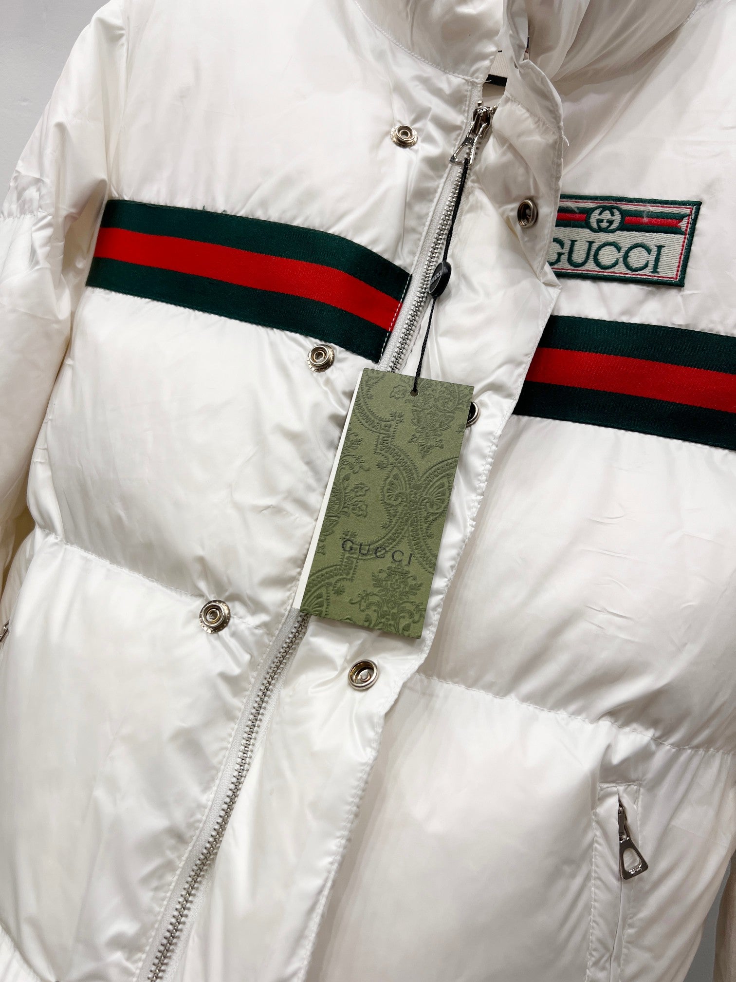 Gucci white puffer jacket close-up with front zipper and stripe trim