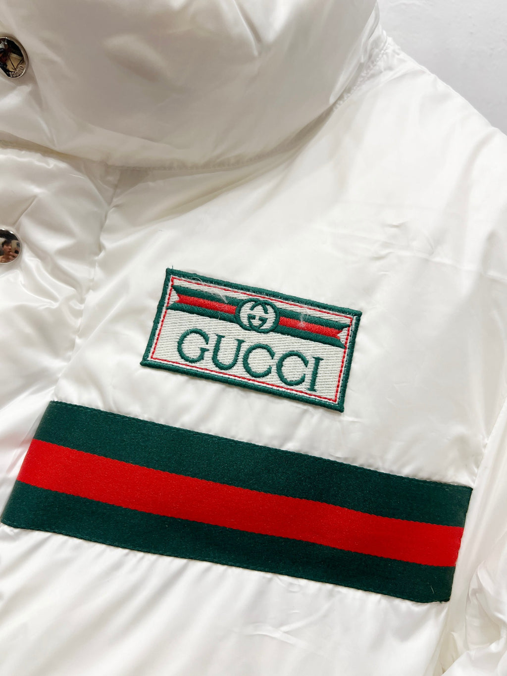 Gucci logo patch on white puffer jacket with green and red stripe band