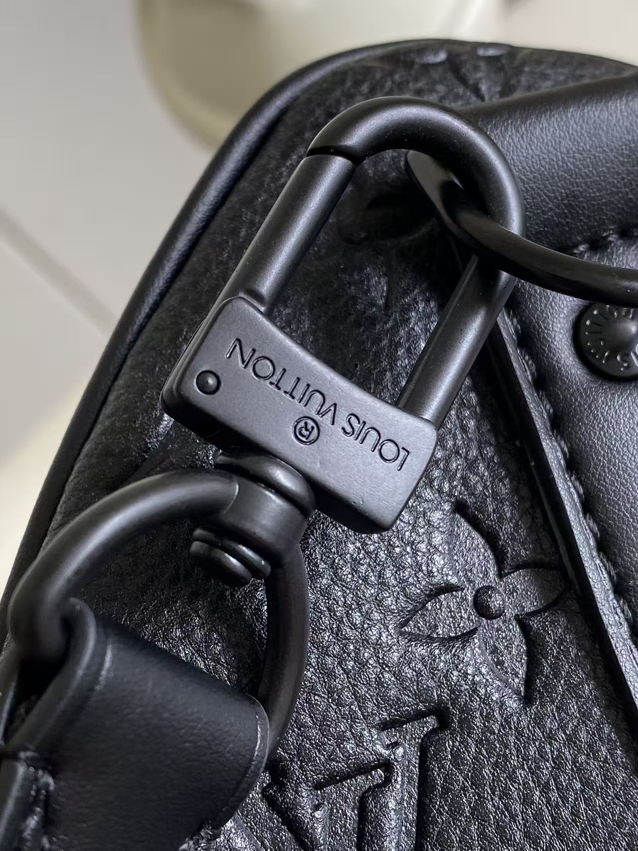 Louis Vuitton handle clasp on dark navy monogram bag, metal hardware close-up