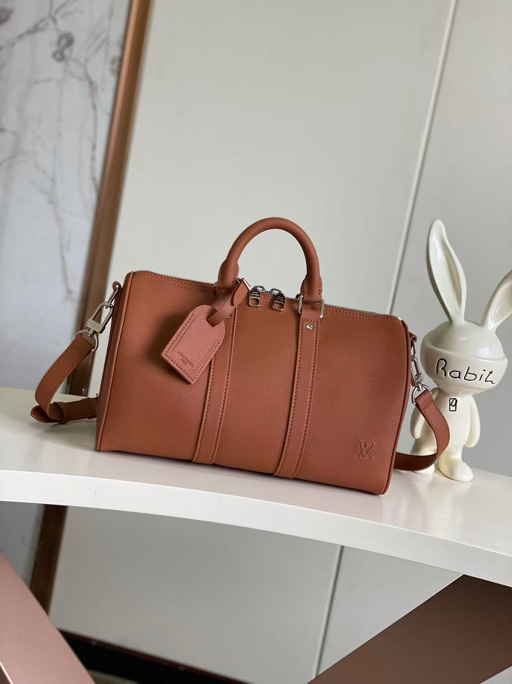 Brown leather structured handbag with top handles and crossbody strap, zipper front panels