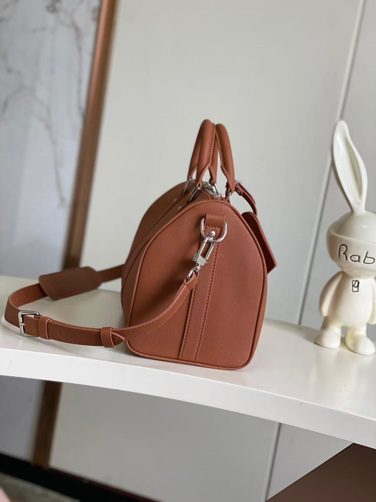 Brown leather barrel-shaped handbag with silver zipper hardware and adjustable shoulder strap
