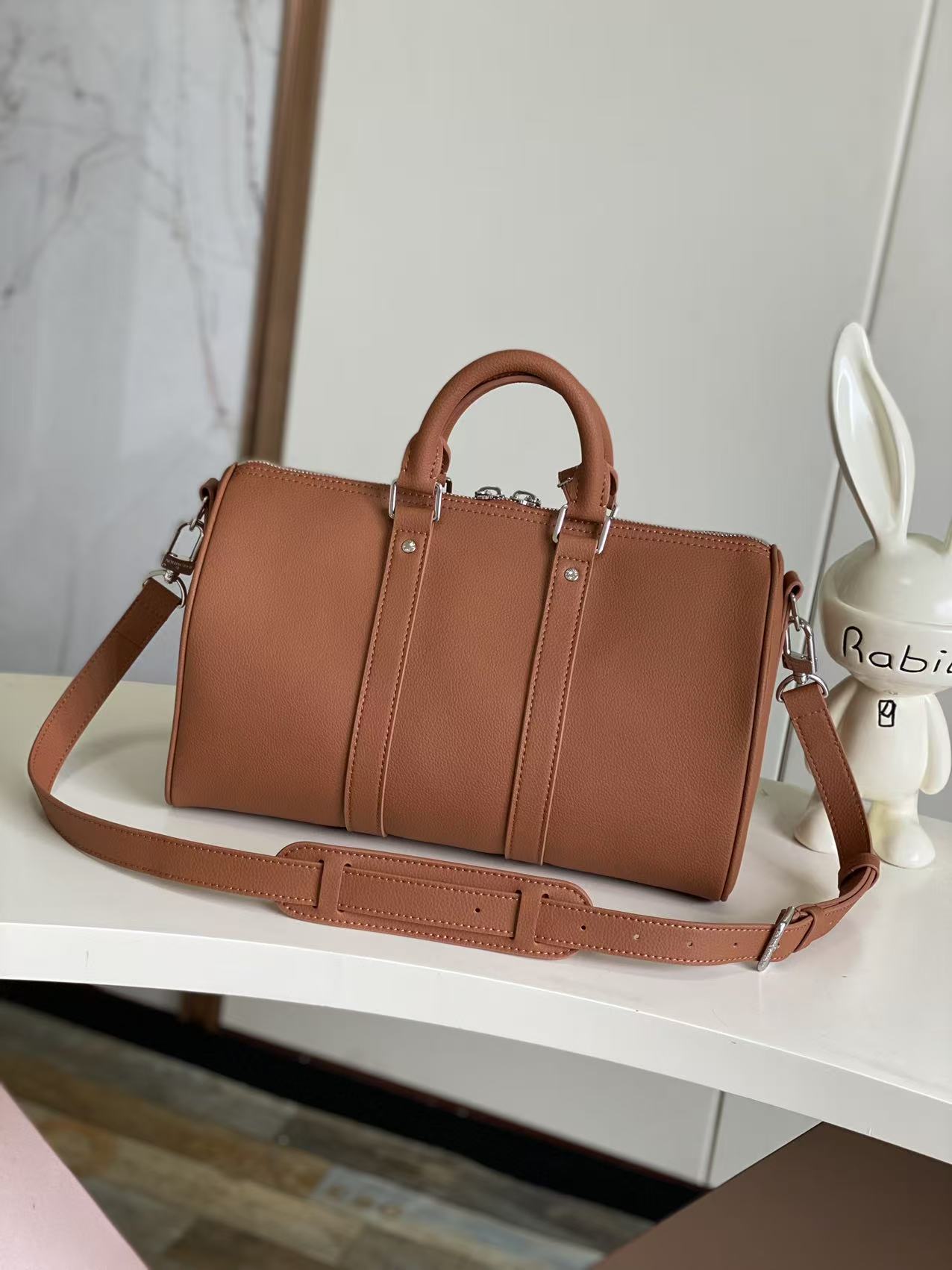 Brown leather top-handle handbag with crossbody strap and stitched front panel design