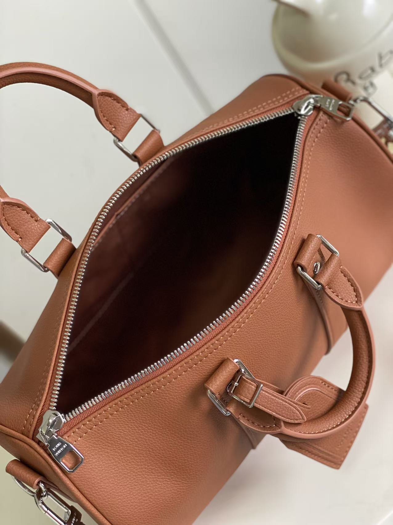 Brown leather handbag open view showing dark interior lining and inner strap pocket