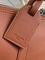 Brown leather handbag with stitched interior label pocket and perforated edge stitching