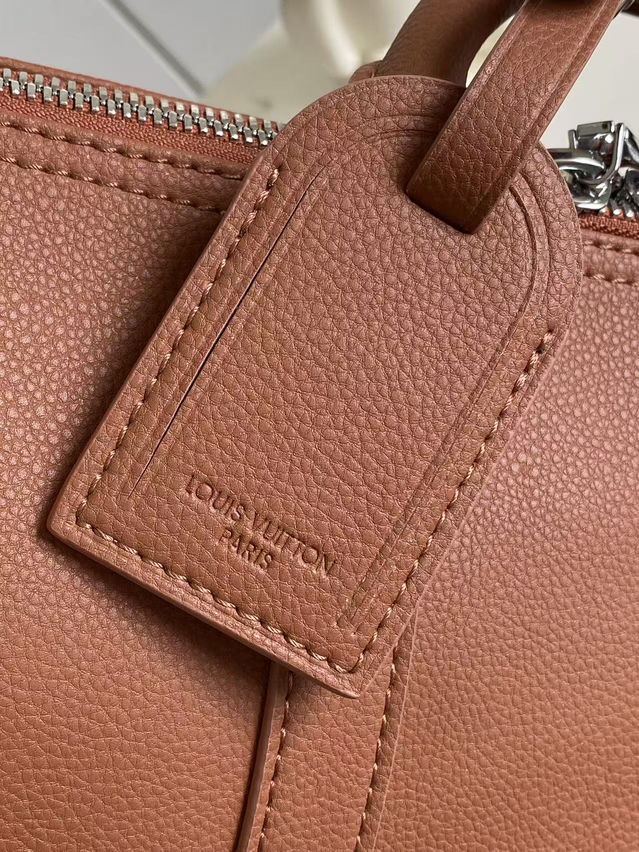 Brown leather handbag with stitched interior label pocket and perforated edge stitching