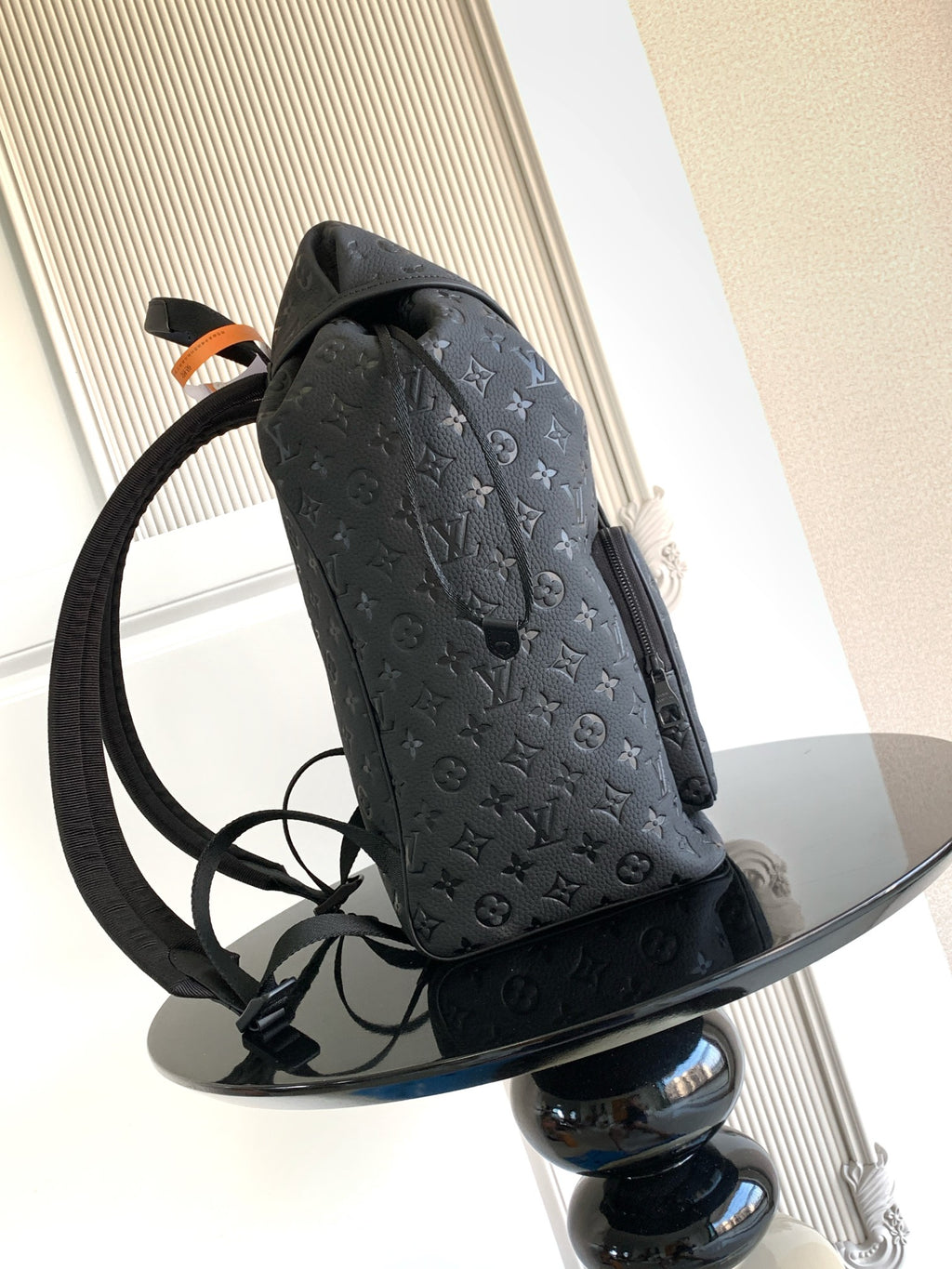 Louis Vuitton monogram backpack in dark gray with side profile and long shoulder strap
