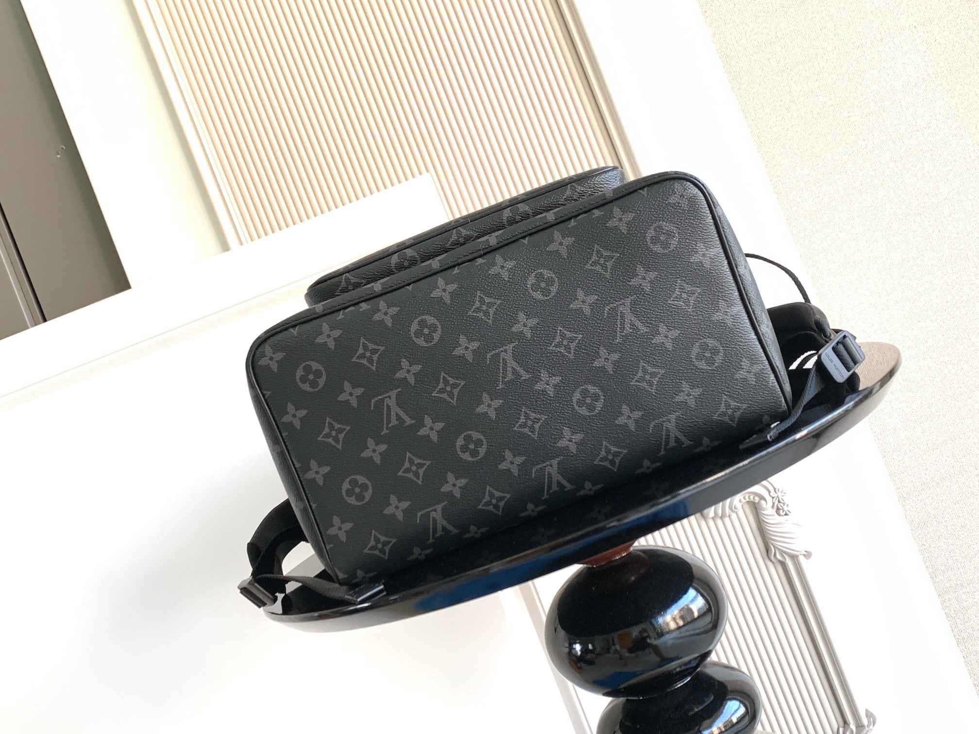 Monogram backpack angled view with front flap pocket and adjustable straps; dark