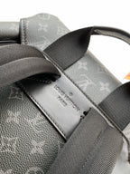 Monogram backpack strap and leather label patch on dark gray fabric
