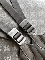Gray monogram backpack strap with metal buckle and stitched leather edging