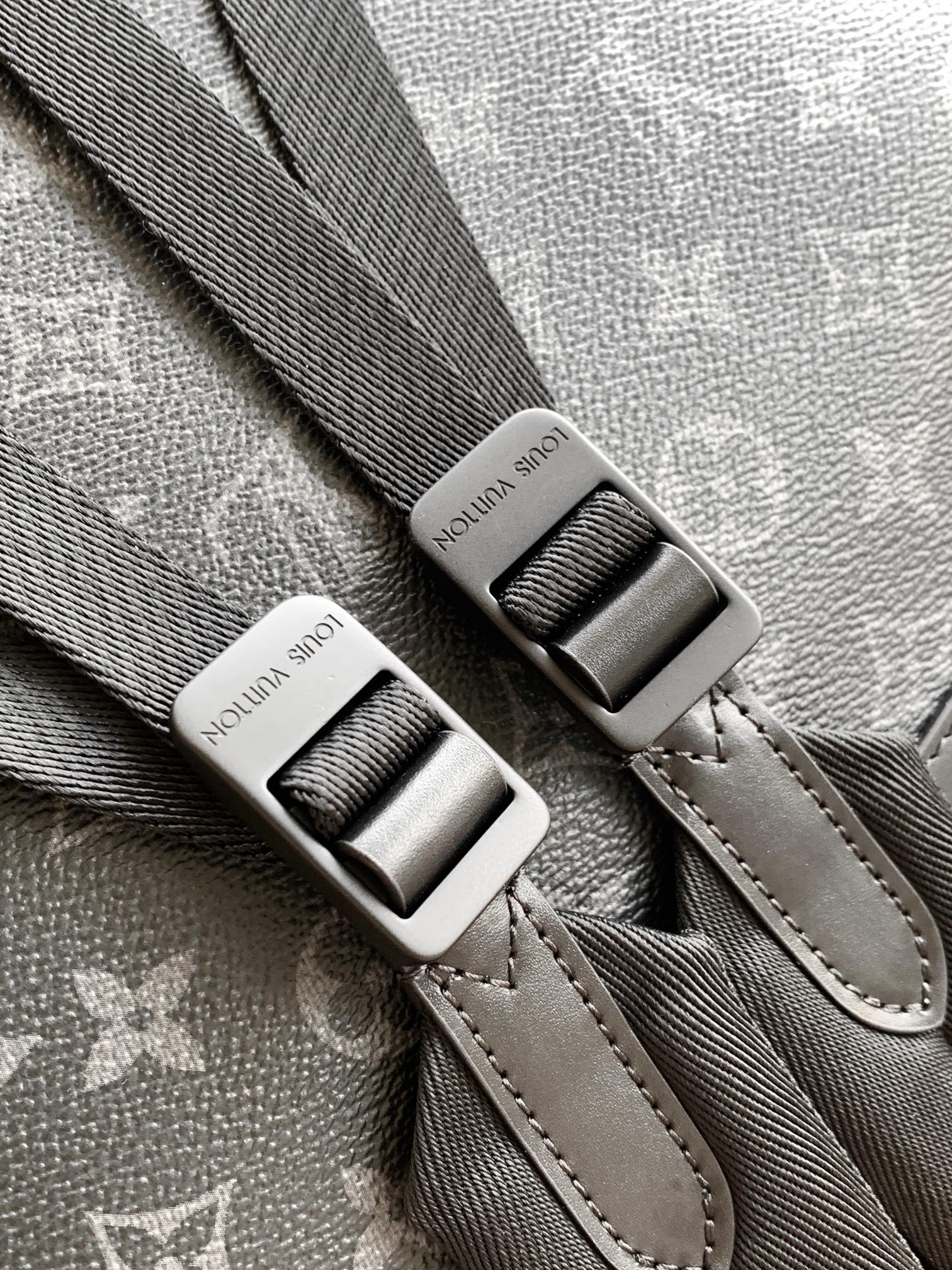 Gray monogram backpack strap with metal buckle and stitched leather edging