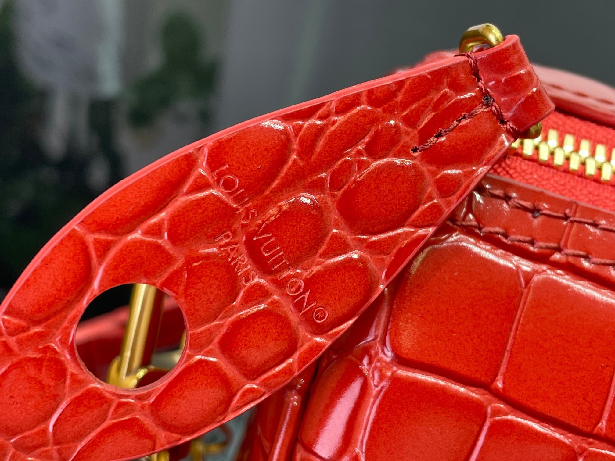 Louis Vuitton red croc-embossed leather corner detail with gold ring and zip hardware