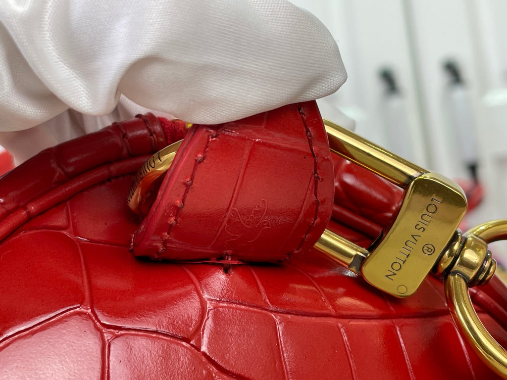 Louis Vuitton red strap connector with gold clasp and croc-embossed leather texture