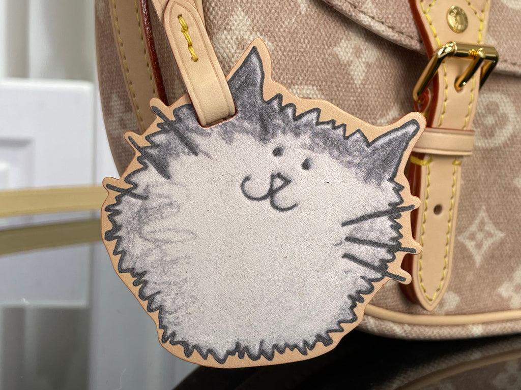 Louis Vuitton cat-shaped charm on bag with tan leather strap and monogram fabric