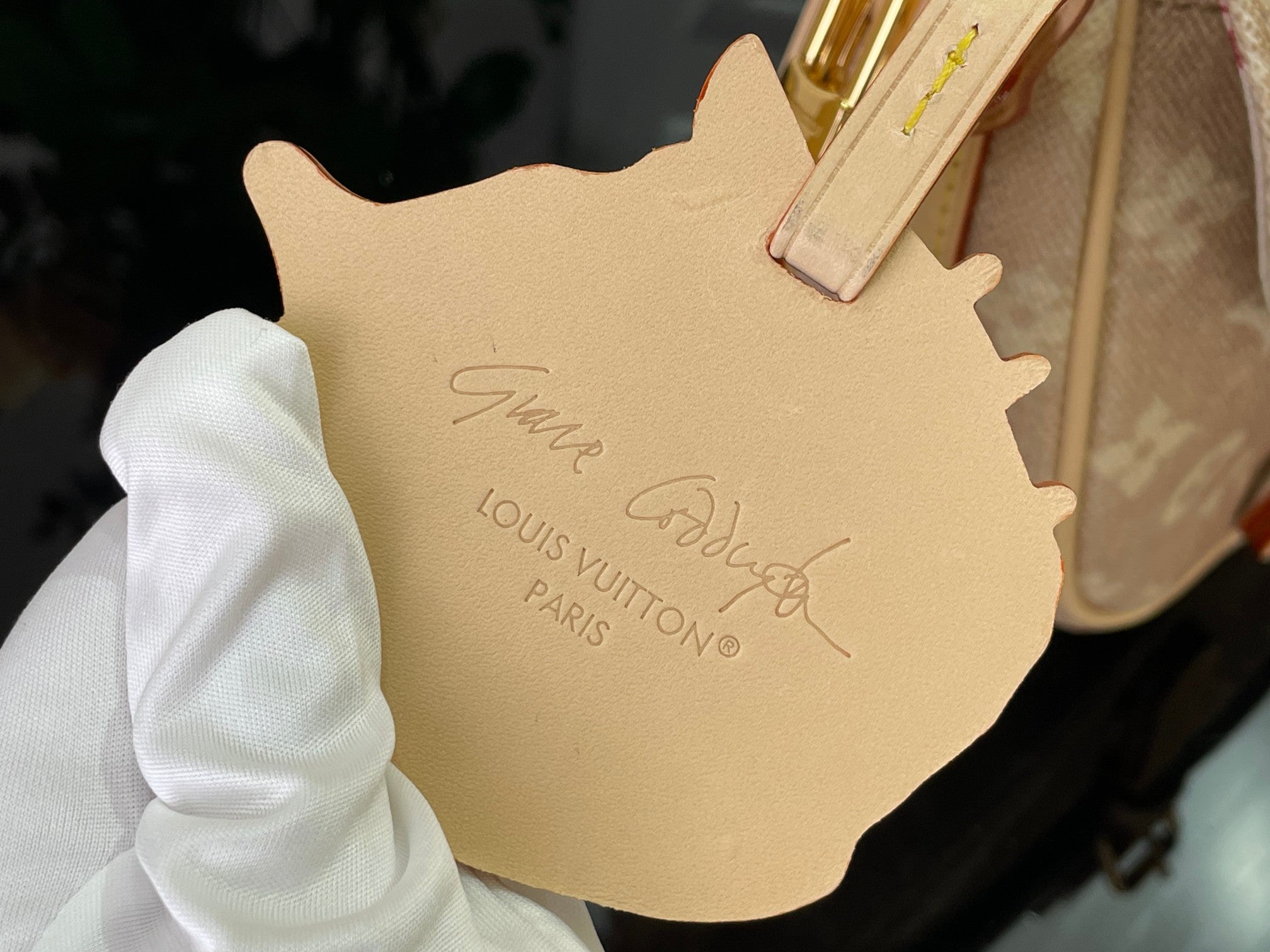 Louis Vuitton leather bag tag in light beige with embossed logo and script
