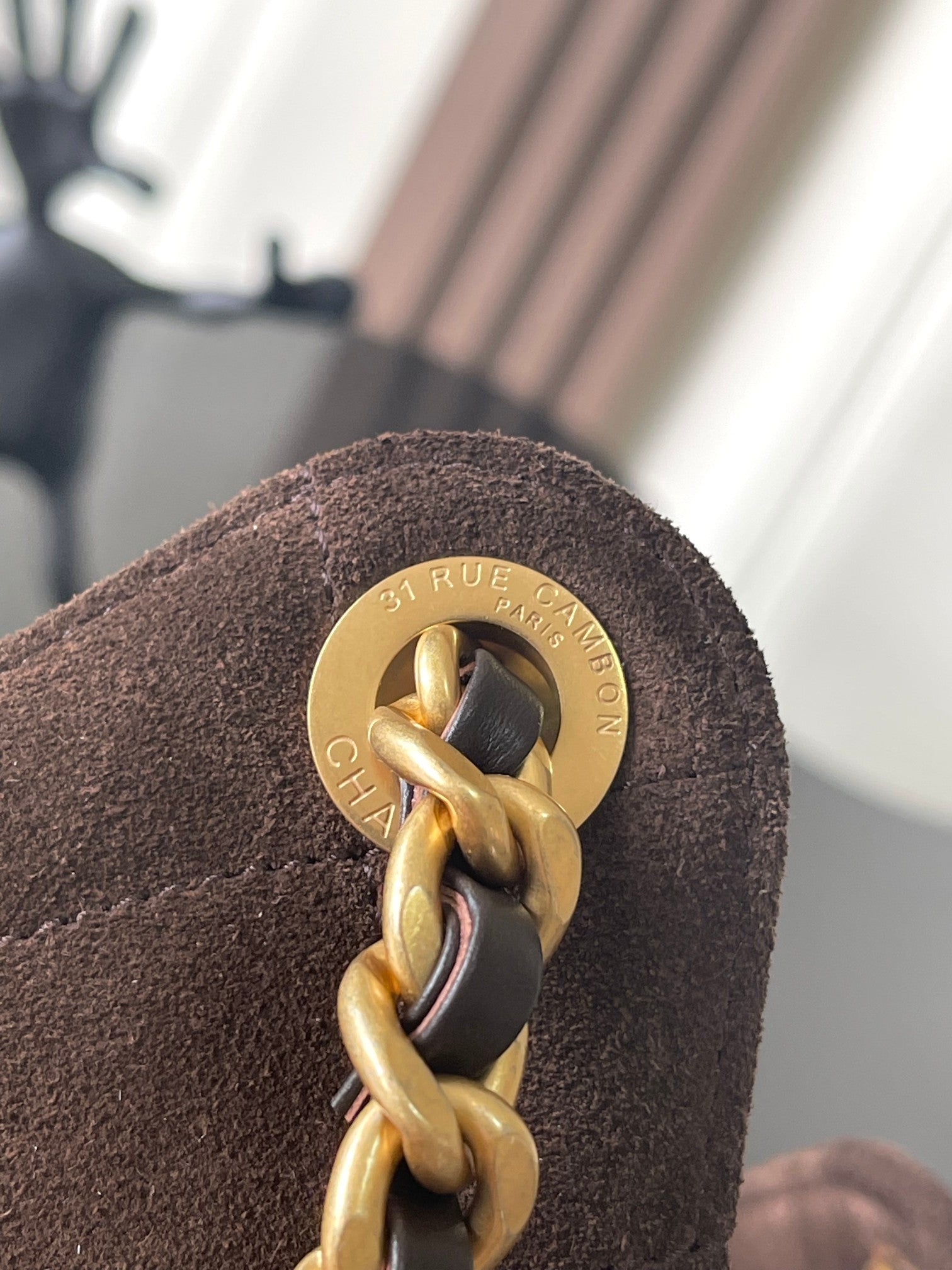 Chanel bag hardware close-up: gold turn-lock ring with stamped logo plate