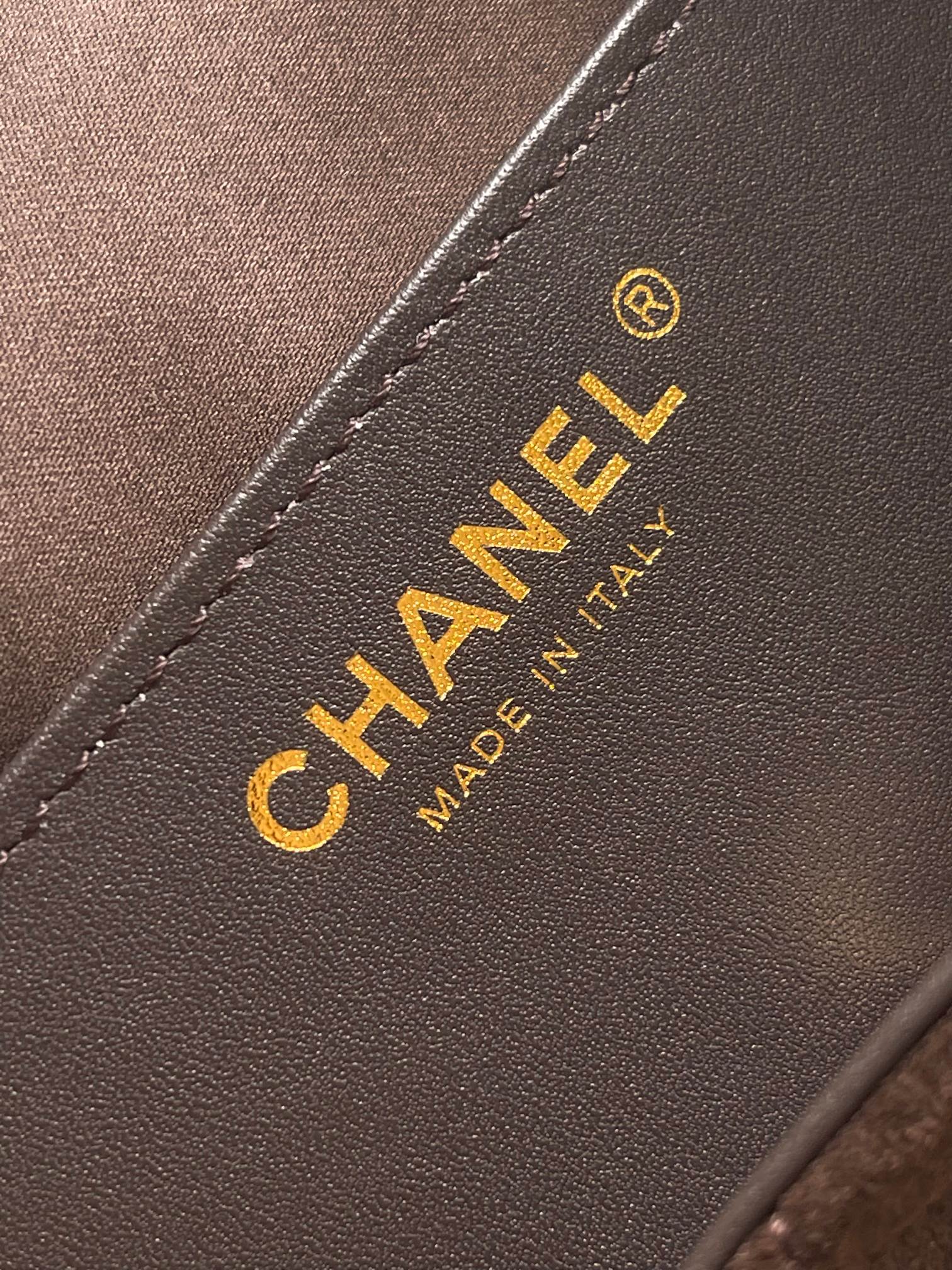 Chanel logo patch on dark brown leather with gold lettering and stitched edge