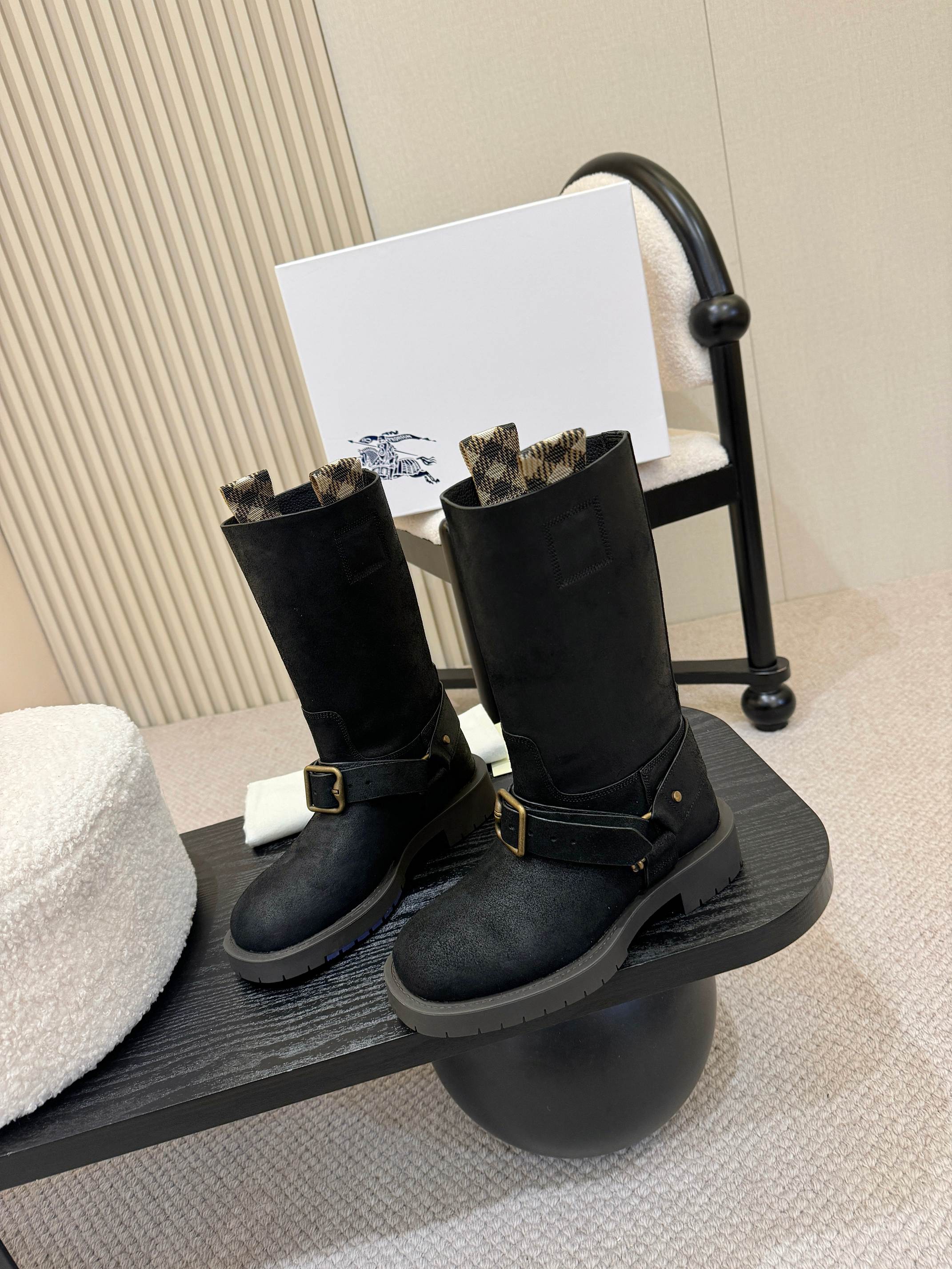 Black mid-calf boots with gold buckle straps, angled view