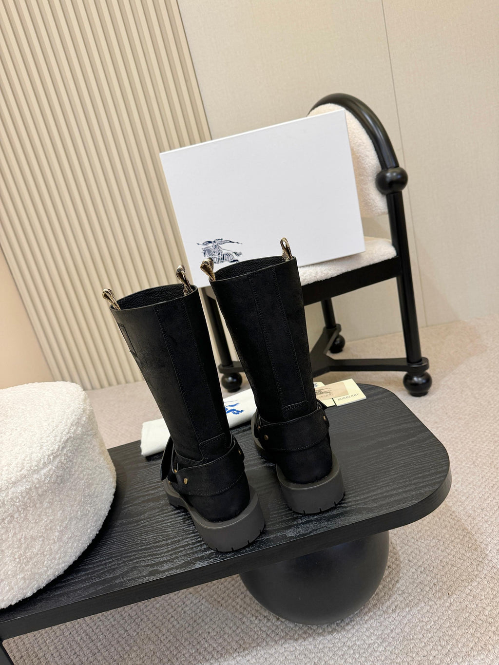 Black mid-calf boots with gold buckle straps, front view on stand