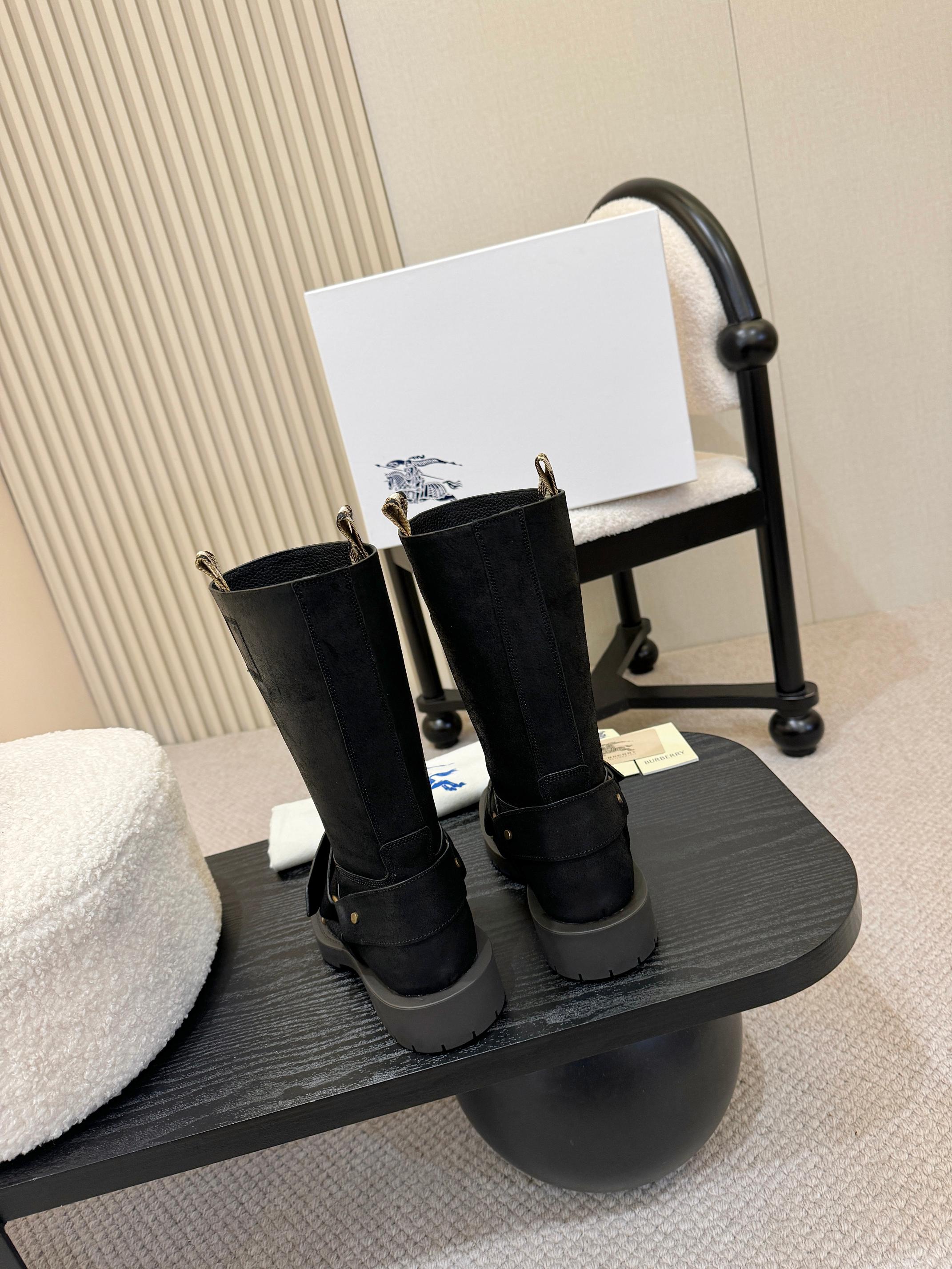 Black mid-calf boots with gold buckle straps, front view on stand