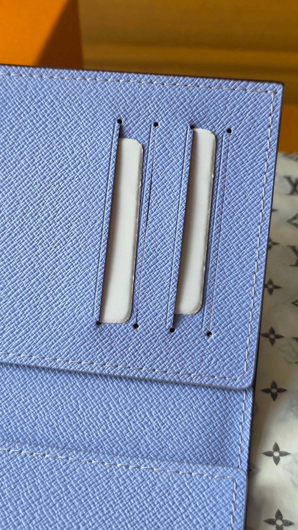 Light blue small pouch with two vertical metal slots on textured flap