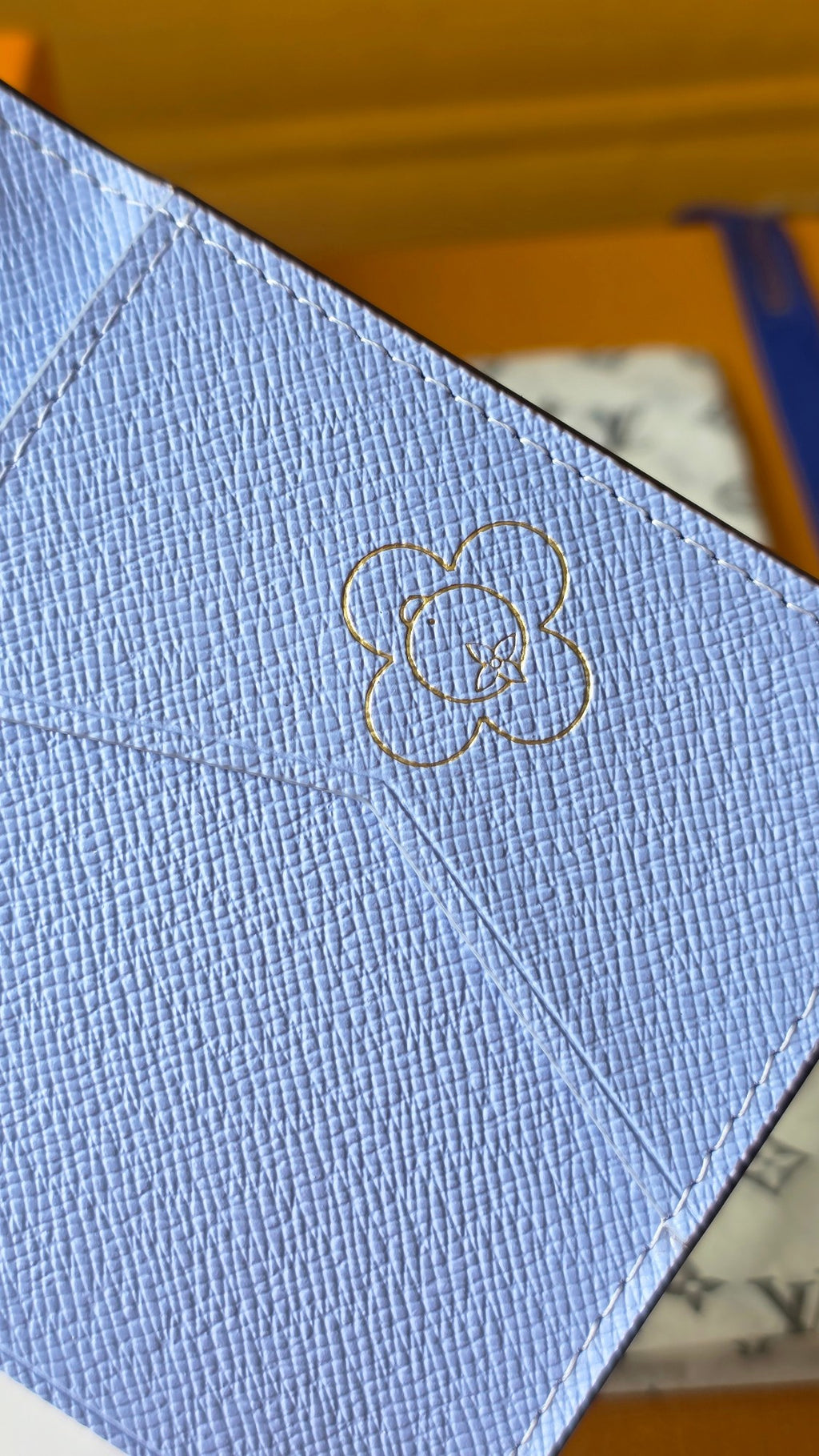 Light blue small pouch with line-drawn clover emblem emboss