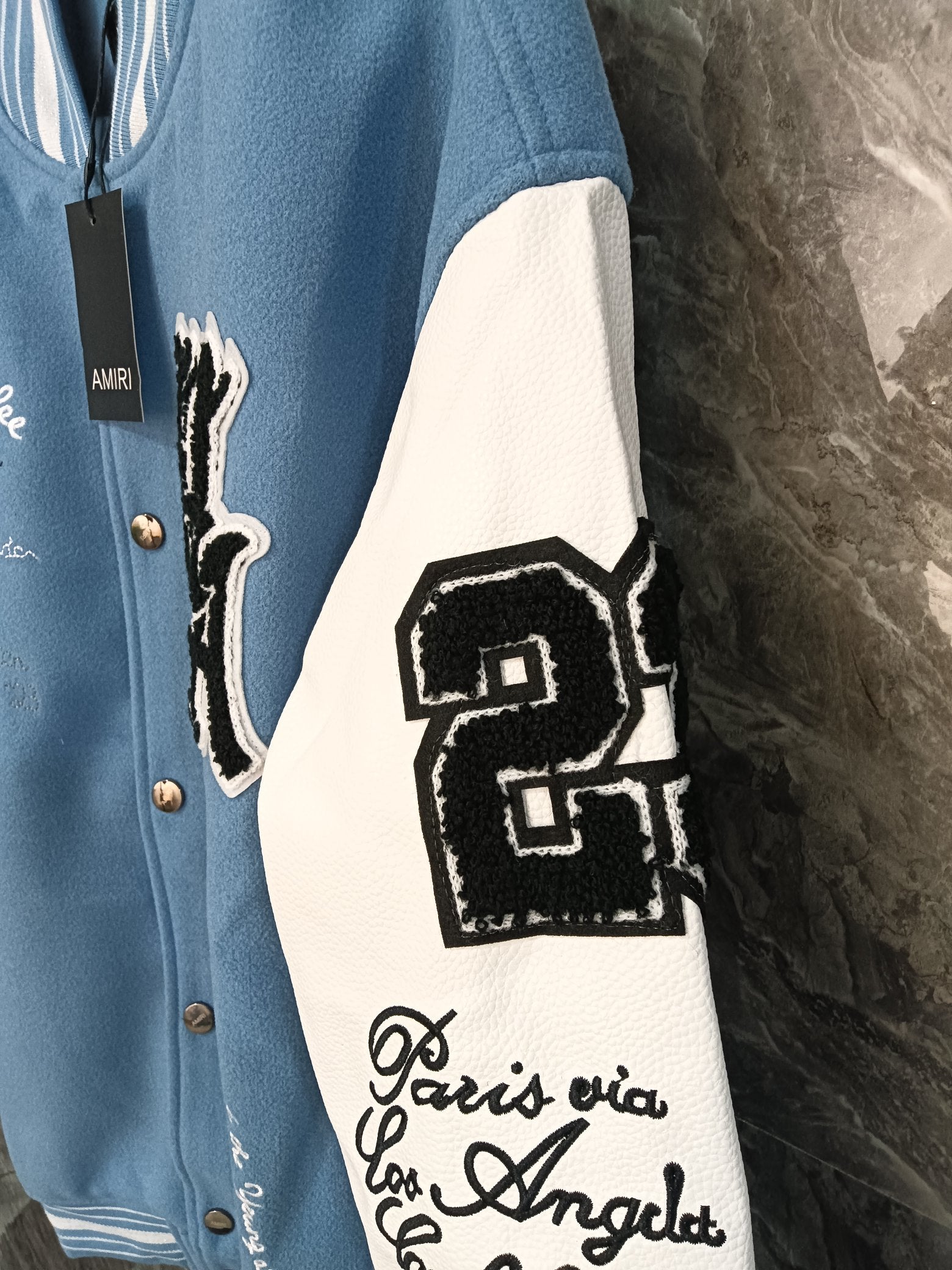 Blue varsity jacket with white sleeve panels and black embroidered crest patch