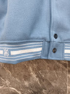 Light blue varsity jacket hem with striped ribbing and three dark button placket
