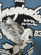 Embroidered graphic on blue varsity jacket: rider detail with “2023” markings