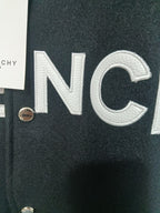 Givenchy varsity jacket close-up: large white 'NC' logo on black knit
